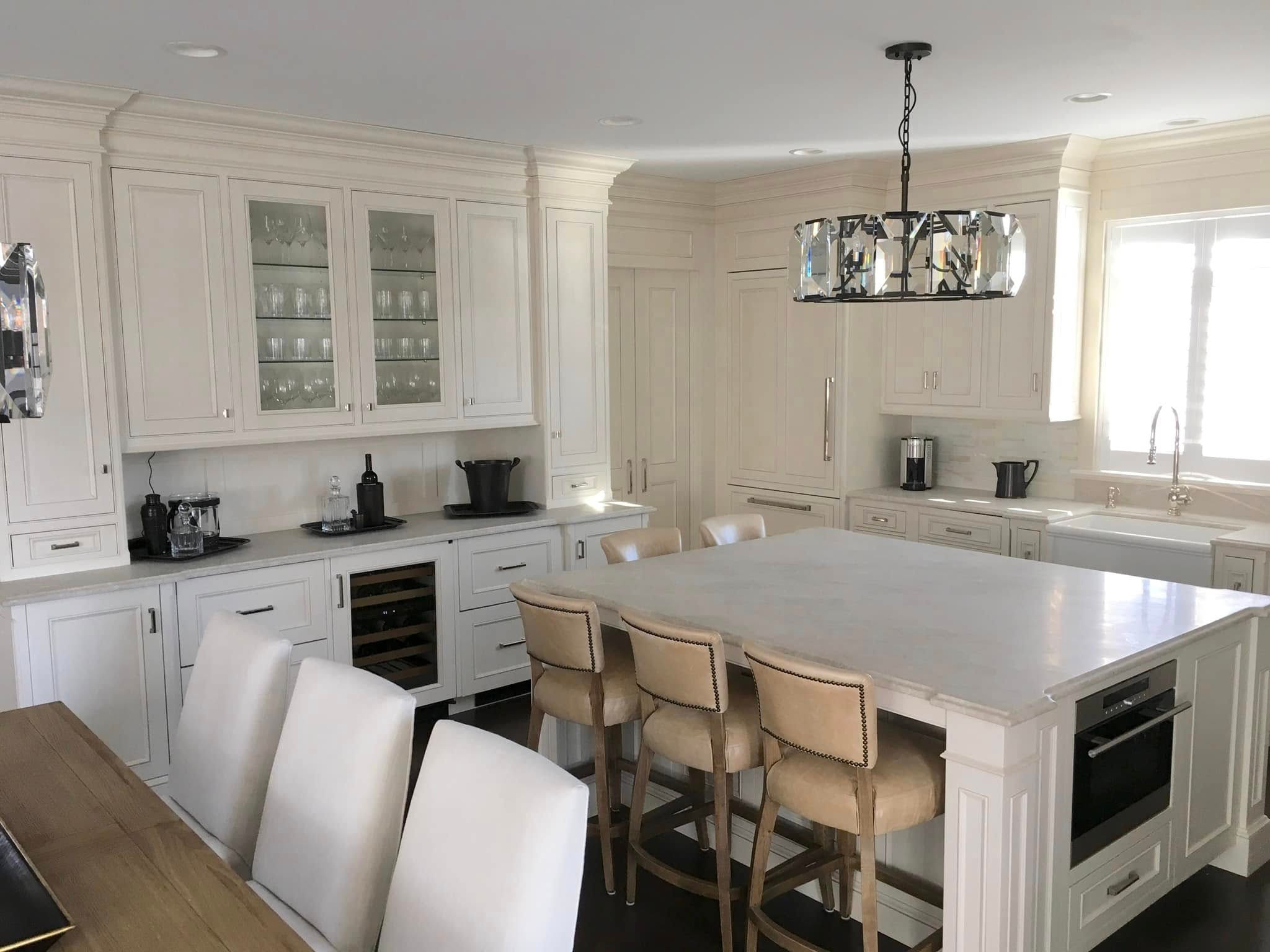 Elegant white kitchen with oversized island, wine fridge and crystal chandelier