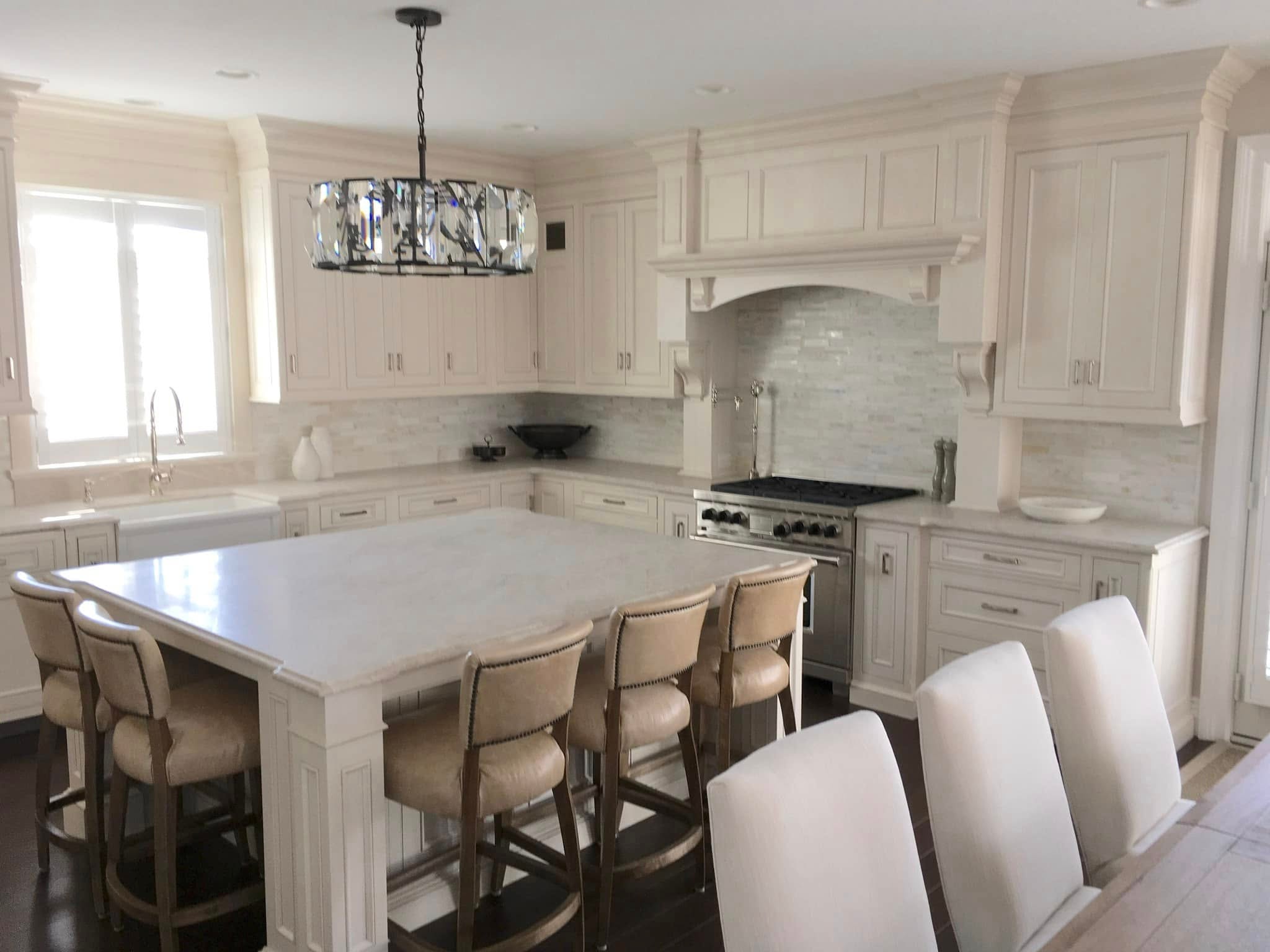 Bright white kitchen with marble island, farmhouse sink and professional range