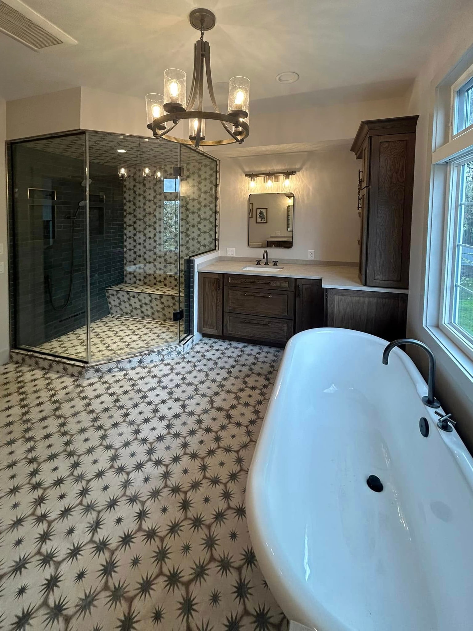 Spa bathroom with freestanding tub, patterned tile floor and glass shower