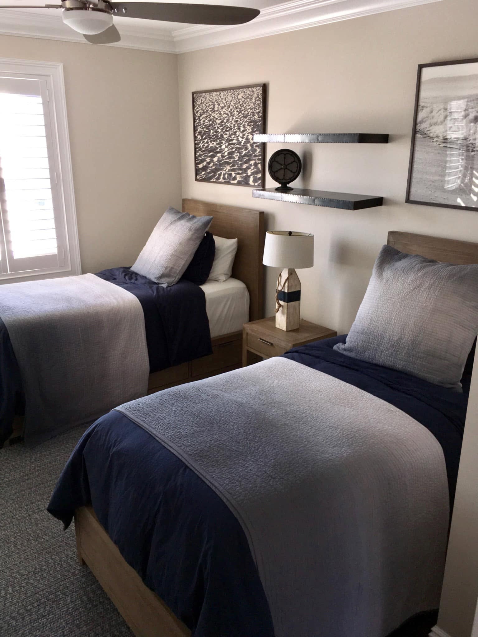 Guest bedroom with twin beds, navy bedding and coastal artwork