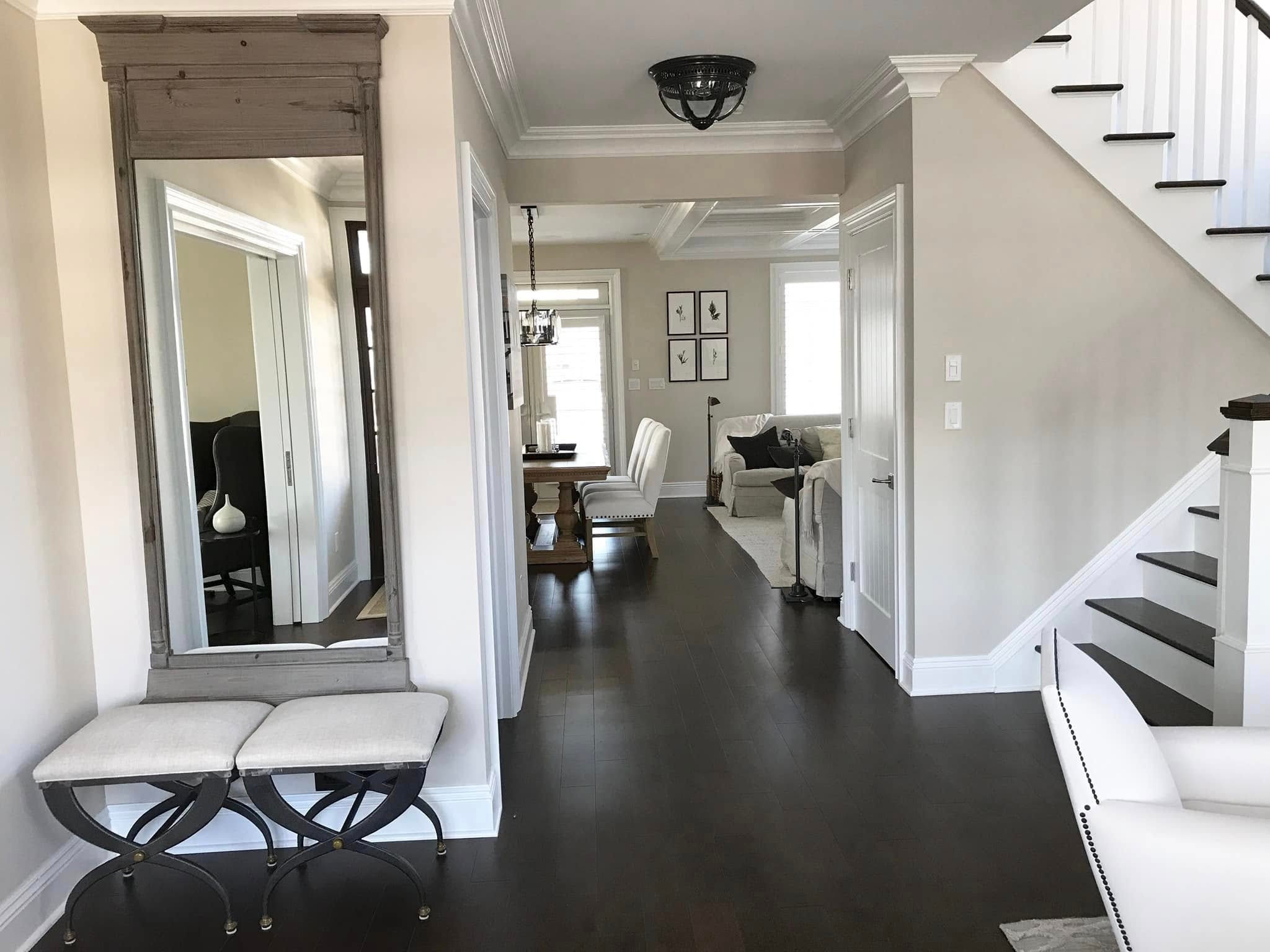 Bright entryway with floor-to-ceiling mirror, dark hardwood floors and open staircase